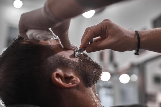 Haarverzorging. Herenkapsels in kapsalons. Kapper maakt een kapsel en baard aan zijn cliënt.