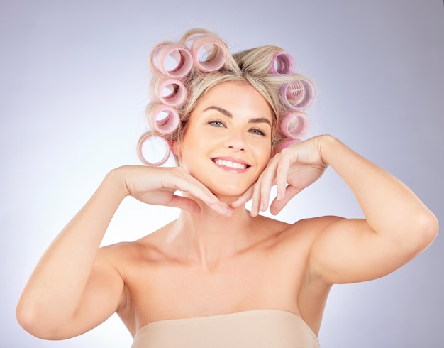 Haarverzorgingsrollers en portret van een vrouw in een studio die een natuurlijk mooi en krullend kapsel doet Zelfzorg gelukkig en aantrekkelijk vrouwelijk model met krulspelden voor schoonheid geïsoleerd door een grijze achtergrond