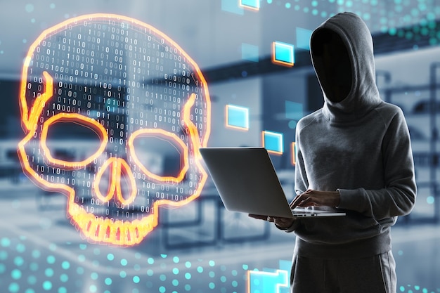 Hacken en online piraterij creatief concept met persoon in hoodie zonder gezicht werken met laptop op donkere kantoorachtergrond en gele schedel digitale hologram dubbele belichting