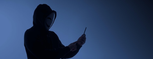 Hacker Anonymous and face mask with smartphone in hand