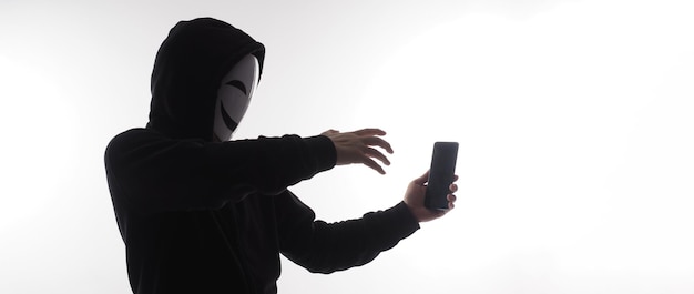 Hacker Anonymous and face mask with smartphone in hand