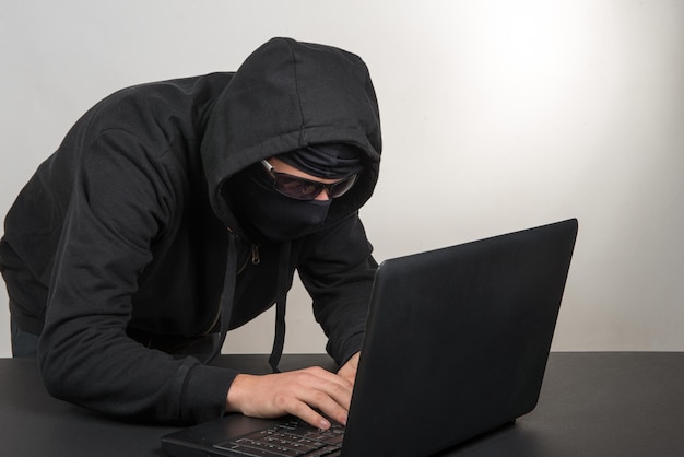 Hacker gebruikt laptop tegen grijze achtergrond