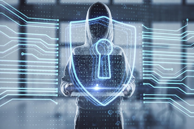 Hacker holding laptop computer with abstract glowing secure web\
safety and protection hologram on blurry office interior background\
hacking and data theft concept double exposure