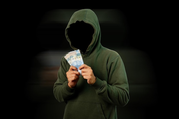 Хакер, держащий бумажные деньги в рупиях, изолированный на черном фоне в режиме размытия движения