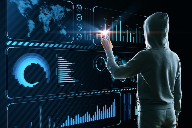 パーカーのハッカーは、暗い背景に地図を持つ創造的な輝く青いビジネス チャート インターフェイスを使用します。技術盗難金融とインターネットの概念
