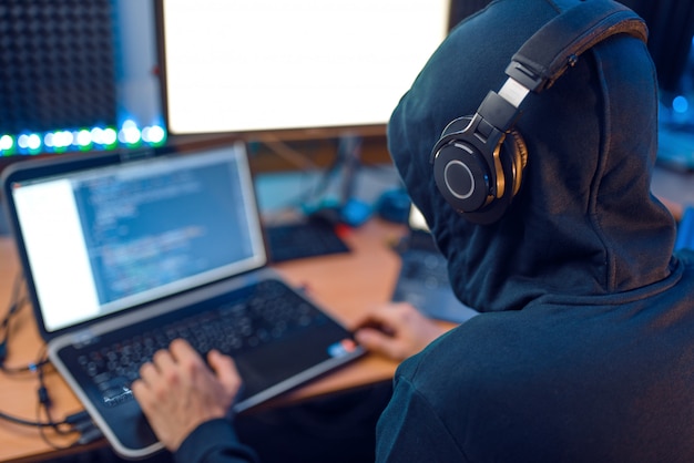 Hacker in de kap zit op laptop, achteraanzicht