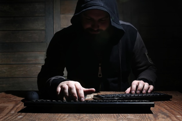 Hacker in de zwarte kap in een kamer met houten wanden