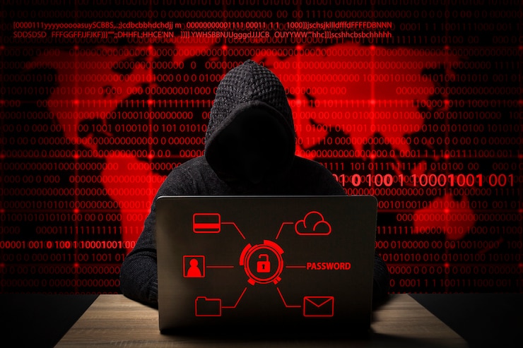 Hacker in een jas met een kap met een laptop zit aan de tafel
