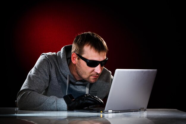 Hacker in een zonnebril met laptop.