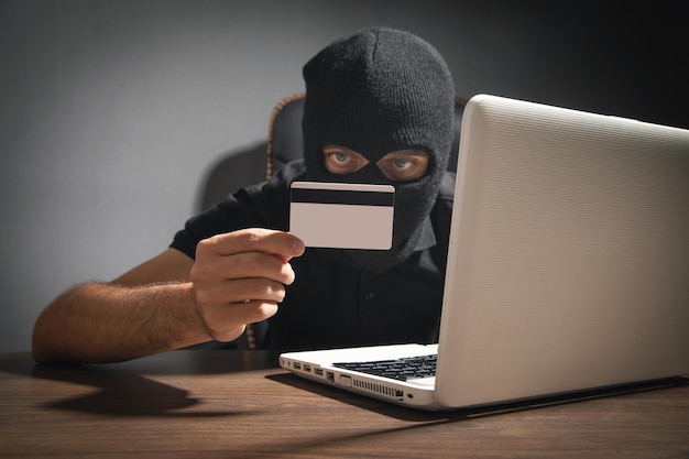 Hacker met creditcard en laptop computer cybercriminaliteit