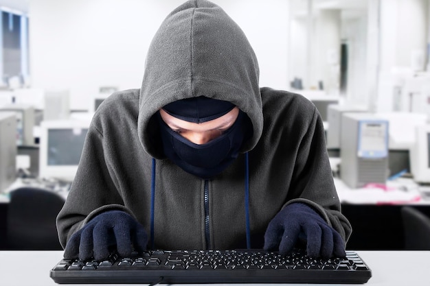 Hacker met toetsenbord aan het bureau in het kantoor