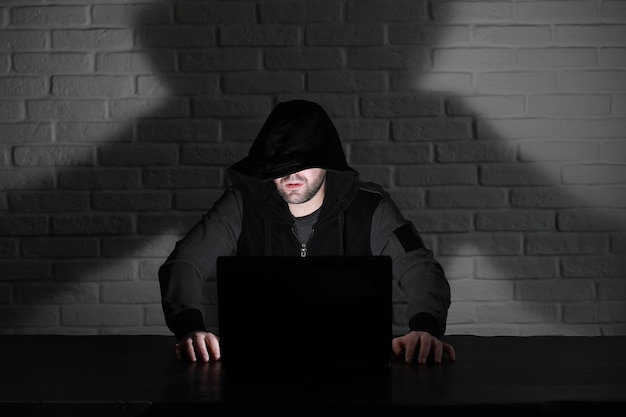 Hacker met zwart masker en kap aan tafel