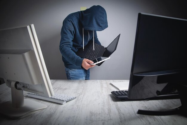 オフィスのコンピューターから情報を盗むハッカーハッキング犯罪者