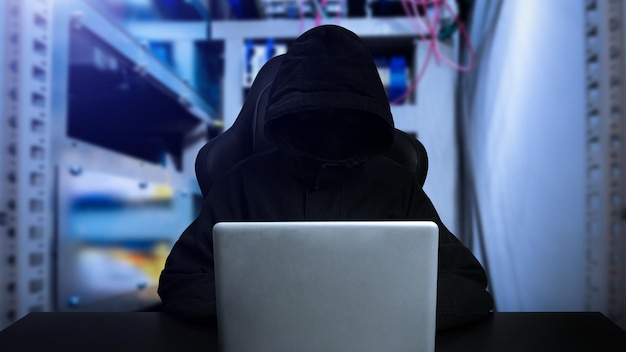 Foto hacker che utilizza un computer con interfaccia digitale mentre è seduto alla scrivania di interni sfocati concetto di hacking e ladro con vr iconxaxa