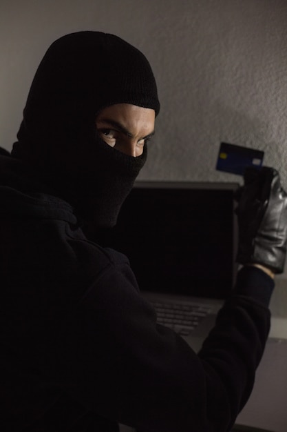 Hacker con carta di debito e laptop