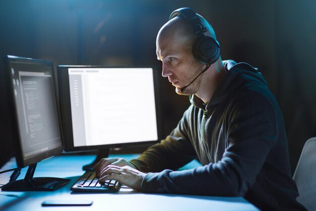 hacker with computer and headset in dark room