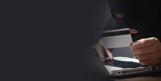 Hacker with credit card and laptop computer Cyber crime