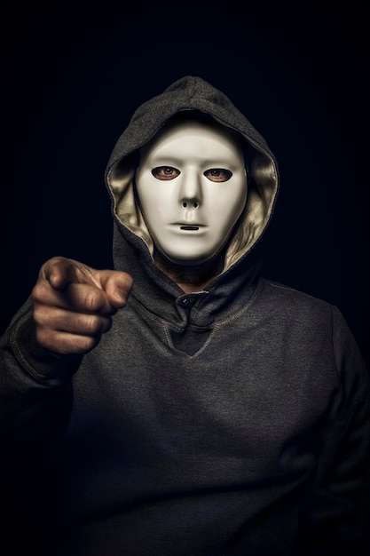 Foto hacker con maschera bianca con la mano che punta alla telecamera