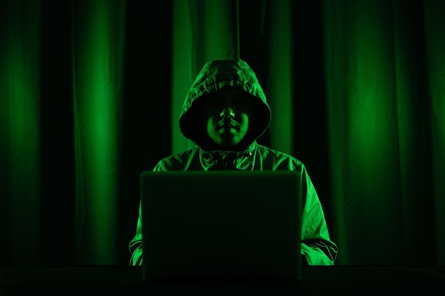 Hackers dragen kappen om hun gezicht te bedekken. Hacken om belangrijke informatie te stelen. Gebruik een computer om malwarevirussen los te laten en organisaties lastig te vallen. Hij zit in de donkere kamer met neonlicht