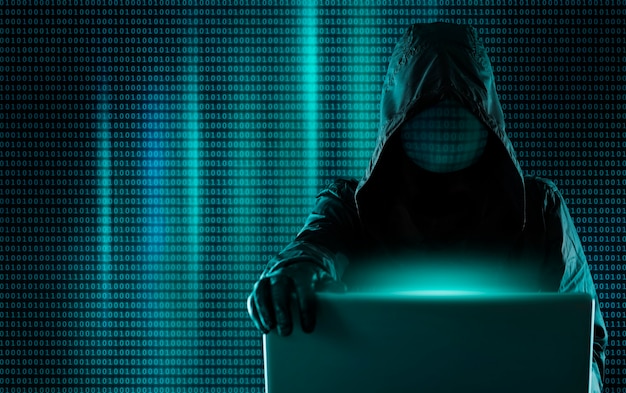 Hacksysteem, cybercrimineel achter een laptop, digitale binaire code op de achtergrond. Hacker breekt in op het systeem