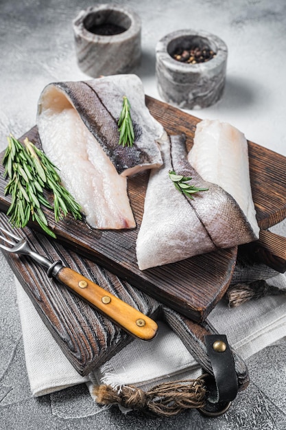 Фото Филе пикши сырое мясо морепродуктов на деревянной доске с травами белый фон вид сверху