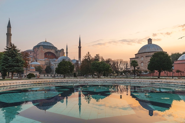 Собор Святой Софии или музей мечети Аясофья и фонтан с отражением на восходе солнца из парка Султана Ахмета в Стамбуле, Турция
