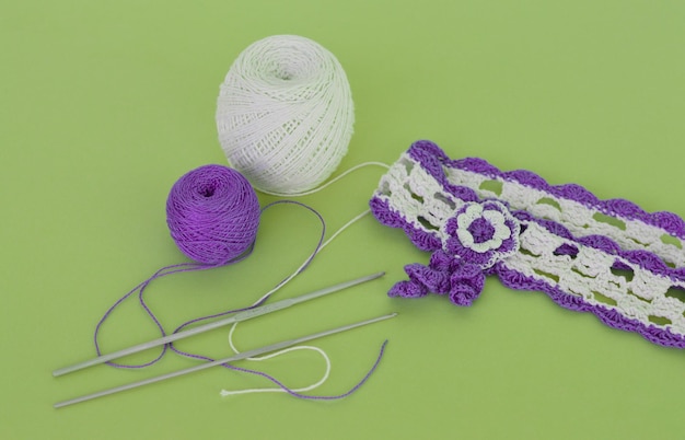 Hair band made white purple cotton threads crocheted threads and crochet hook on a green background