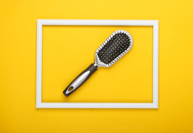 Hair brush on yellow surface with white frame