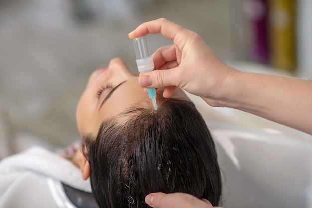 hair care. hair stylist applying keratin on her clients hair