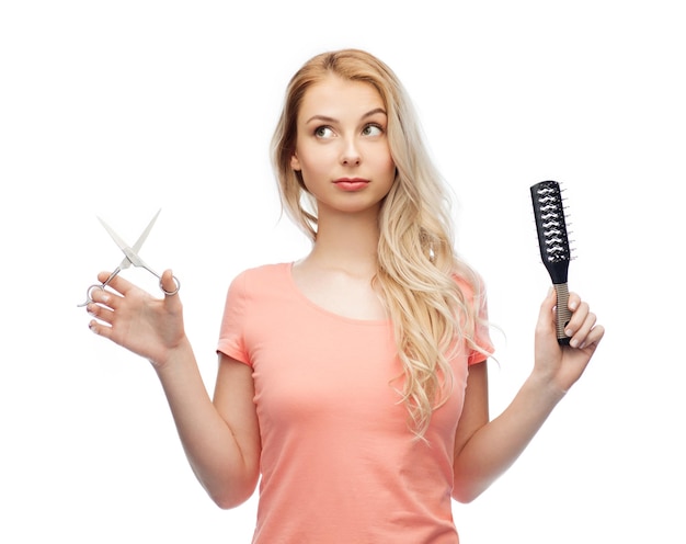 hair care, hairstyle, hairdressing and beauty people concept - young woman or teenage girl with scissors and hairbrush