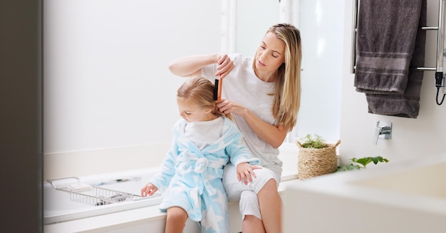 Hair care mother and girl in bathroom with brush and bonding to connect talking and for fun Female lady and daughter or kid doing development child growth and discussion together at home loving