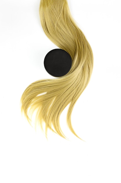 Hair care spa concept Different professional hairdresser tools balsam hair cream and strand of blonde hair on white background flat lay Hairdresser salon concept