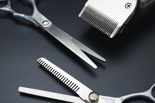 Photo hair clipper and hairdresser scissors on black background mens hairdressing desktop tools shaving