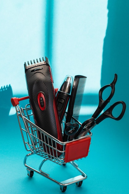 Hair clippers two pairs of scissors and one comb lie in a mini basket on a blue background