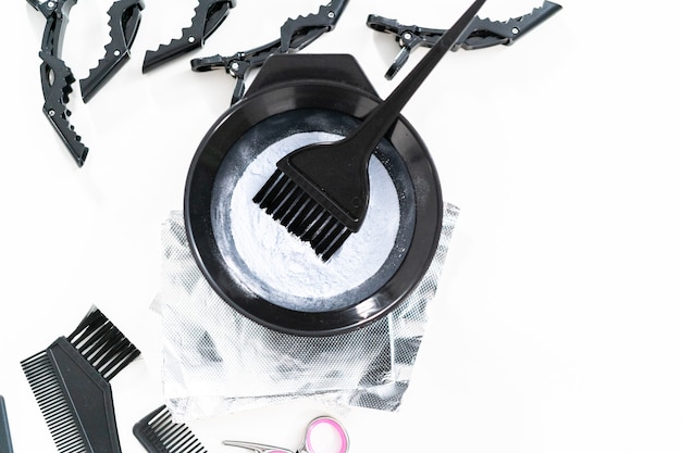 Hair color dye powder in a black plastic mixing bowl on a white background.