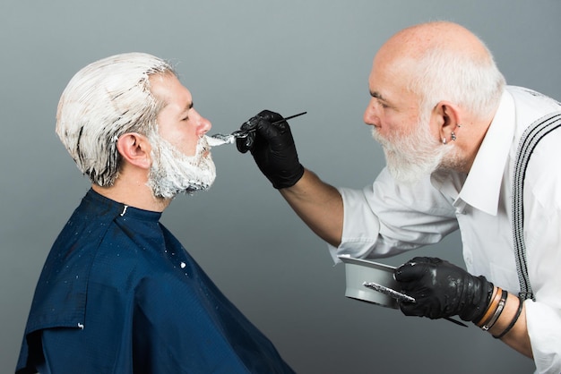 Hair coloring man making of a dyed blond hair for a bearded hipster guy beard coloring man agains gr