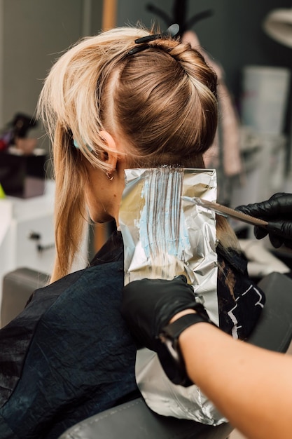Foto colorazione dei capelli in bianco in un salone di bellezza processo di applicazione della tintura ai capelli
