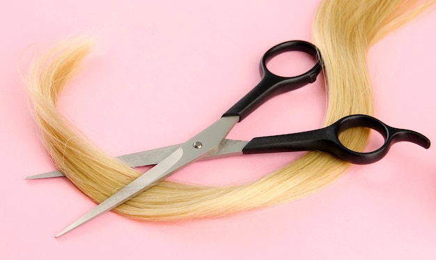 Hair and cutting shears on pink background