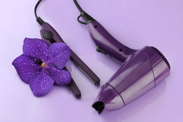 Hair dryer and straighteners on purple background