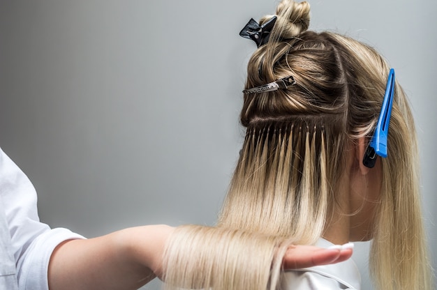 Фото Наращивание волос клиенту крупным планом в салоне красоты