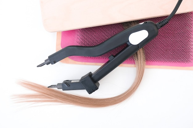 Photo hair extensions tools. strand of natural hair, curling iron on a white background