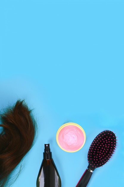 Foto capelli, maschera per capelli, pettine, spray su sfondo blu pastello. concetto di cura dei capelli. copia spazio, vista dall'alto.