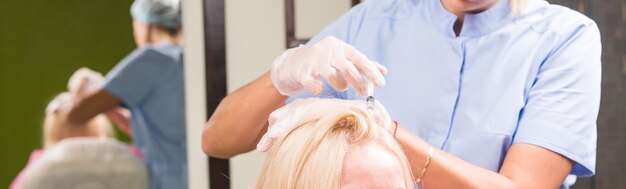 Hair loss concept  female beautician makes injection of vitamins and minerals in the scalp