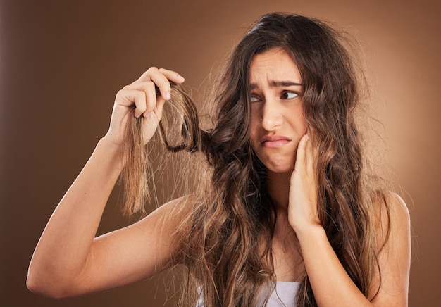 Foto crisi di perdita di capelli e donna preoccupata in studio per bellezza disordinata e danni su sfondo marrone cura dei capelli fallita e ragazza triste frustrata da doppie punte deboli o alopecia forfora e isolata