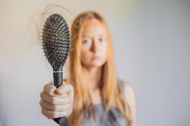 女性の概念の脱毛櫛の上の多くの失われた髪