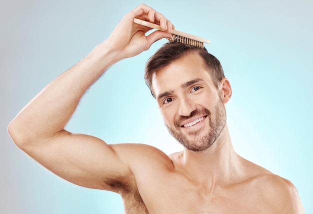 Hair man in portrait and beauty with brush and grooming with hygiene on blue background Cosmetic care clean and fresh with hairstyle wellness and routine with skin glow and towel for haircare