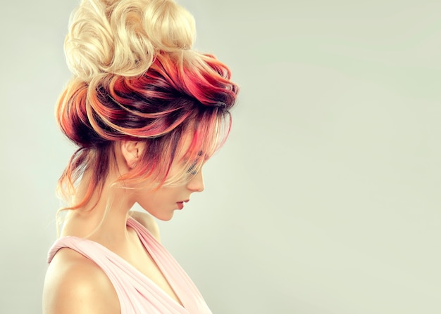 Hair painting. young attractive woman with multi colored hair gathered in elegant evening hairstyle with big blonde bun. hairdressing and coloration of hair