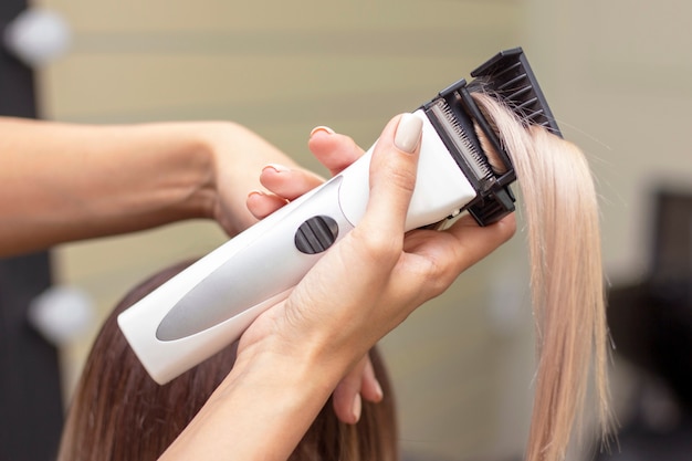 Hair polishing procedure. the hairdresser in the salon polishes the hair with a special machine for polishing hair. cutting off split ends of hair. vertical photo