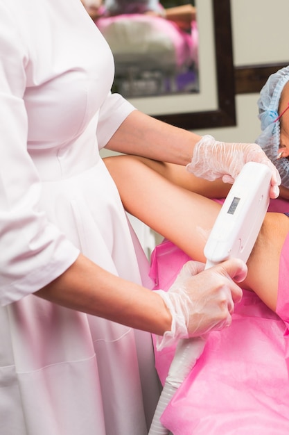 Hair removal cosmetology procedure from a therapist at cosmetic beauty spa clinic. Laser epilation. Cosmetology and SPA concept.