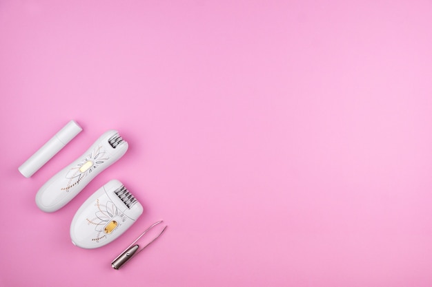 Hair removal kit of four devices on a pink background